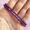 Detailopname van twee natuurlijke paarse amethist kralenarmbanden op de hand - Paarse Amethist(Armband 24)