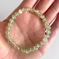 Detailopname van de elastische armband met lichtgroene natuurstenen kralen op een hand - Lichtgroen(Armband 26)
