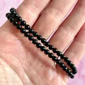 Detail van de dubbellaagse zwarte obsidiaan kralenarmband met elastisch koord op roze achtergrond - Diepzwart(Armband 29)