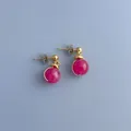 Detaillierte Nahaufnahme der rosa Steinperlen-Ohrstecker mit Golddrahtwicklung und Steckern - Ohrringe / Rosa