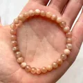 Macro-opname van gefacetteerde zonnesteen kralen armband op een elastisch koord in de hand - Oranje Roze Zonnesteen(Armband 35)