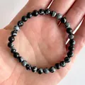 Detailopname van sneeuwvlok obsidiaan kralenarmband met 8mm natuursteen op de hand - Sneeuwvlok Obsidiaan Stijl(Armband 37)