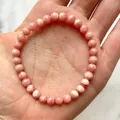 Detailopname van een rekbare armband van roze rhodochrosiet kralen met natuurlijke textuur - Rhodochrosiet Stijl(Armband 46)