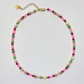 Makroaufnahme einer Kette aus bunten Steinen und Süßwasserperlen mit goldenem Herzanhänger - Rosa/Tiefrot/Grün