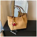 Dettaglio di una grande borsa tote in pelle scamosciata marrone con ciondolo a pompon rosso - Con Ciondolo / Giallo
