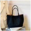Grande borsa tote nera opaca con fodera marrone su una valigia metallica argento - Con Ciondolo / Nero