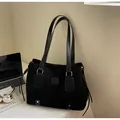 Detail of black canvas tote bag with leather straps next to laptop and art book - Black