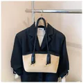 Détail du sac cabas en daim beige avec bordures en cuir noir sur un support en métal - Avec Pendentif / Kaki