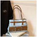 Détail du sac cabas en denim bleu clair avec anses en cuir marron et fermoir rotatif - Avec Pendentif / Bleu