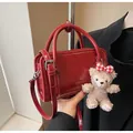 Detail of red leather square handbag with round handle and plush bear charm accent - With Pendant / Red