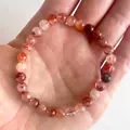Elastische kralenarmband met 8mm rode natuursteen kralen op de hand van een persoon - Roodbruin Ijs Crack(Armband 57)