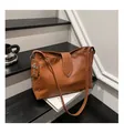 Detail van bruin kiezelleder met zilveren klinknagels en kruisvormige bedel aan de tas - Bruin