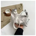 Detail of white glossy shoulder bag featuring silver hardware and side zipper pockets - White
