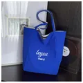 Detail of blue canvas tote bag with white lettering and rich fabric texture - One Size / Blue