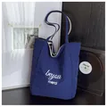 Detail of navy canvas tote bag featuring white merci text and striped lining interior - One Size / Dark Blue