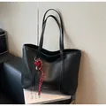 Close-up of black tote bag featuring woven texture and a red heart pendant detail - With Pendant / Black