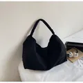 Grande borsa tote in tela nera con manici larghi in un ambiente minimalista - Nero