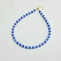 Dettaglio di perle occhio di gatto blu e perline bianche su collana con chiusura a moschettone oro - Collana con trama opale / 38+5cm / Blu Grande Bianco Piccolo