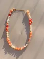 Detail van ketting met oranje onregelmatige stenen, parels en gouden verlengketting - Oranje Rood Steen Parel Stijl