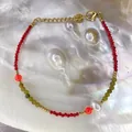 Close-up of 18K gold beaded bracelet with natural stones and pearl on shell background - Red Cut Beads with Pearl and Orange Beads