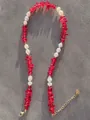 Dettaglio di perline rosse e perle irregolari con chiusura a moschettone dorata e catena - Stile Perla Barocca Perlina Rossa