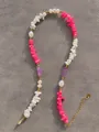 Dettaglio macro di una collana bohémien con pietre irregolari colorate e perle fini - Stile Boho Rosa Bianco Oro