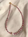 Detail van gekleurde facetgeslepen stenen kralen en een grote witte zoetwaterparel aan gouden ketting - Roze Grijze Kralen Stijl (3)