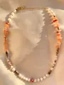 Dettaglio di collana boho con perle bianche, pietre arancioni e chiusura a moschettone oro - Pietra Arancione Bianco Marrone