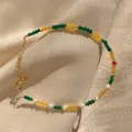 Detail of multi-color beads, freshwater pearls and 18K gold-plated chain on champagne silk - Green Yellow Red Beads with Irregular Pearl