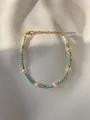 Detailed macro view of 18K gold-plated beaded bracelet with pearls and green beads - Green White Striped Beads with Irregular Pearl