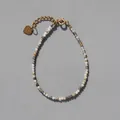 Detail van natuursteen kralenarmband met gouden hartbedeltje en verstelbaar verlengkettinkje - Grijs Bruin Tint (1)