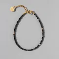 Detail van natuursteen kralenarmband met 18k vergulde ketting en hartje hanger - Zwart