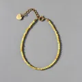 Macro-opname van kralenarmband met natuursteen, 18k gouden hartbedeltje en verstelbare ketting - Lichtgeel