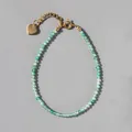 Detailed shot of turquoise beaded bracelet with 18k gold heart charm and clasp - Turquoise Green