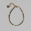 Macro view of dainty multi-color natural stone beaded bracelet with 18k gold heart charm - Earth Tone