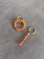 Detailed macro view of asymmetric orange natural stone beaded earrings in gold finish - Heterogeneous Orange Red Imperial Stone Style