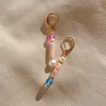 Close-up of asymmetric long drop earrings with mixed natural stones and gold hooks - Pink Textured Column with Colored Bead Style