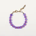 Détail du bracelet en perles violettes avec accents orange et chaîne trombone dorée - Style de perles carrées violettes et perles rondes orange / Taille unique / 17+3cm / Violet