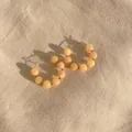 Detail of colorful beads on gold hoop earrings over a textured beige linen background - Light Orange Translucent Stone Hoop Style