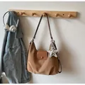 Brown leather crescent shoulder bag with a silver star charm on a wooden wall hook - With Pendant / Khaki