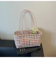 Pink woven hollow basket bag with floral accent on a minimalist book background - Taro Purple
