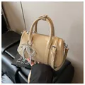 Borsa Boston beige lucida con ciondolo a fiocco di perle e tracolla regolabile - Con Ciondolo / Color Tè al Latte