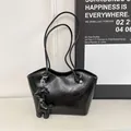 Minimalist black tote bag with wave-edge top, glossy crinkled leather, and dog charm - Black
