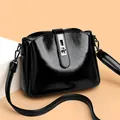 Bolso tipo cubo en cuero negro brillante con cierre giratorio plateado y borde ondulado - Negro
