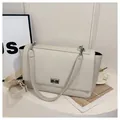 Detail of cream white pebbled leather bag featuring a silver twist-lock and wide strap - White