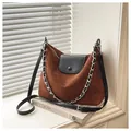 Detail of caramel suede tote bag with decorative silver metal chain on window sill - Brown