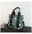 Dark green tote bag with skull floral print featuring wide black straps and silver hooks - Green