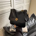 Solid black crossbody bag with a shiny finish and elegant golden flower-shaped lock - Black