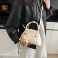 Borsa a conchiglia minimalista bianco crema con ciondolo a orso su un outfit alla moda - Con Ciondolo / Bianco