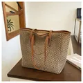 Detailed view of straw tote bag with brown faux leather straps on a wooden table - One Size / Khaki
